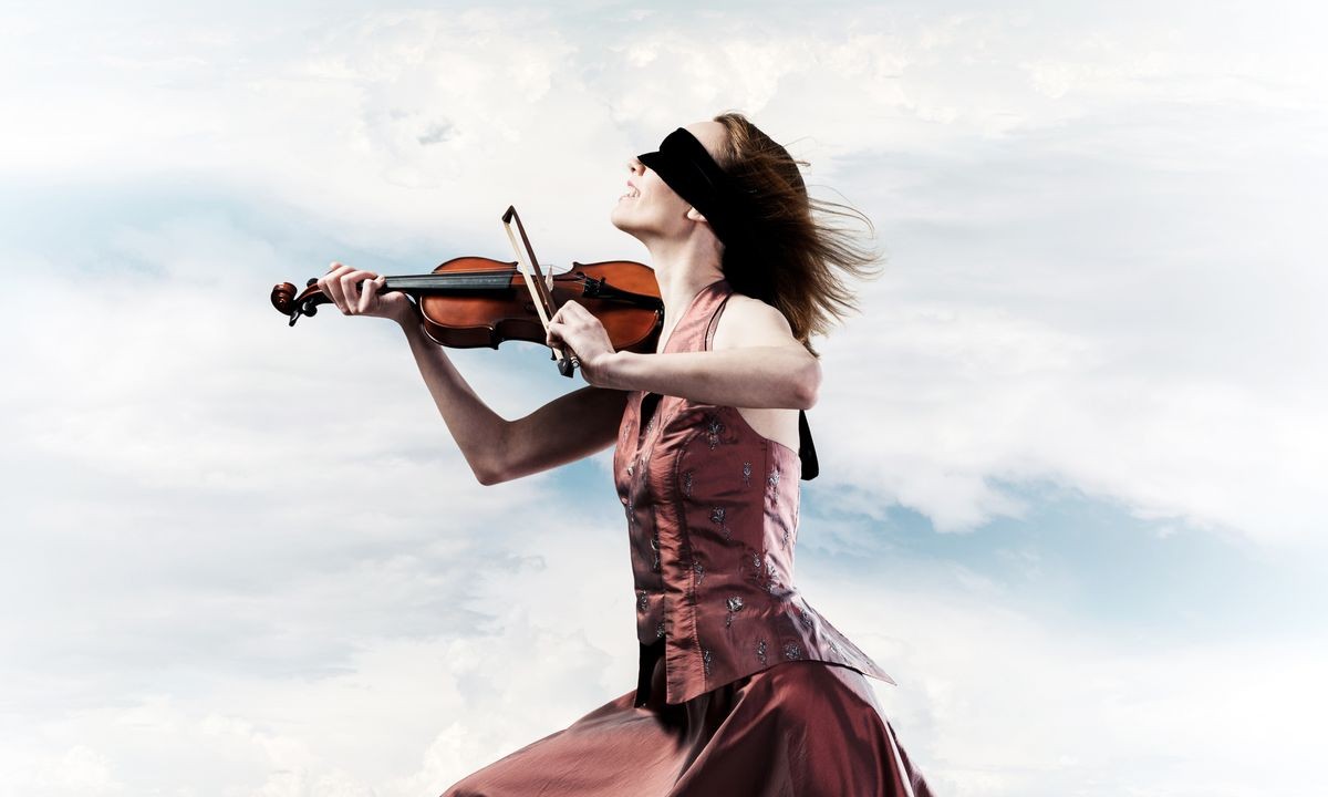 Young attractive girl playing violin over blue sky and cloud